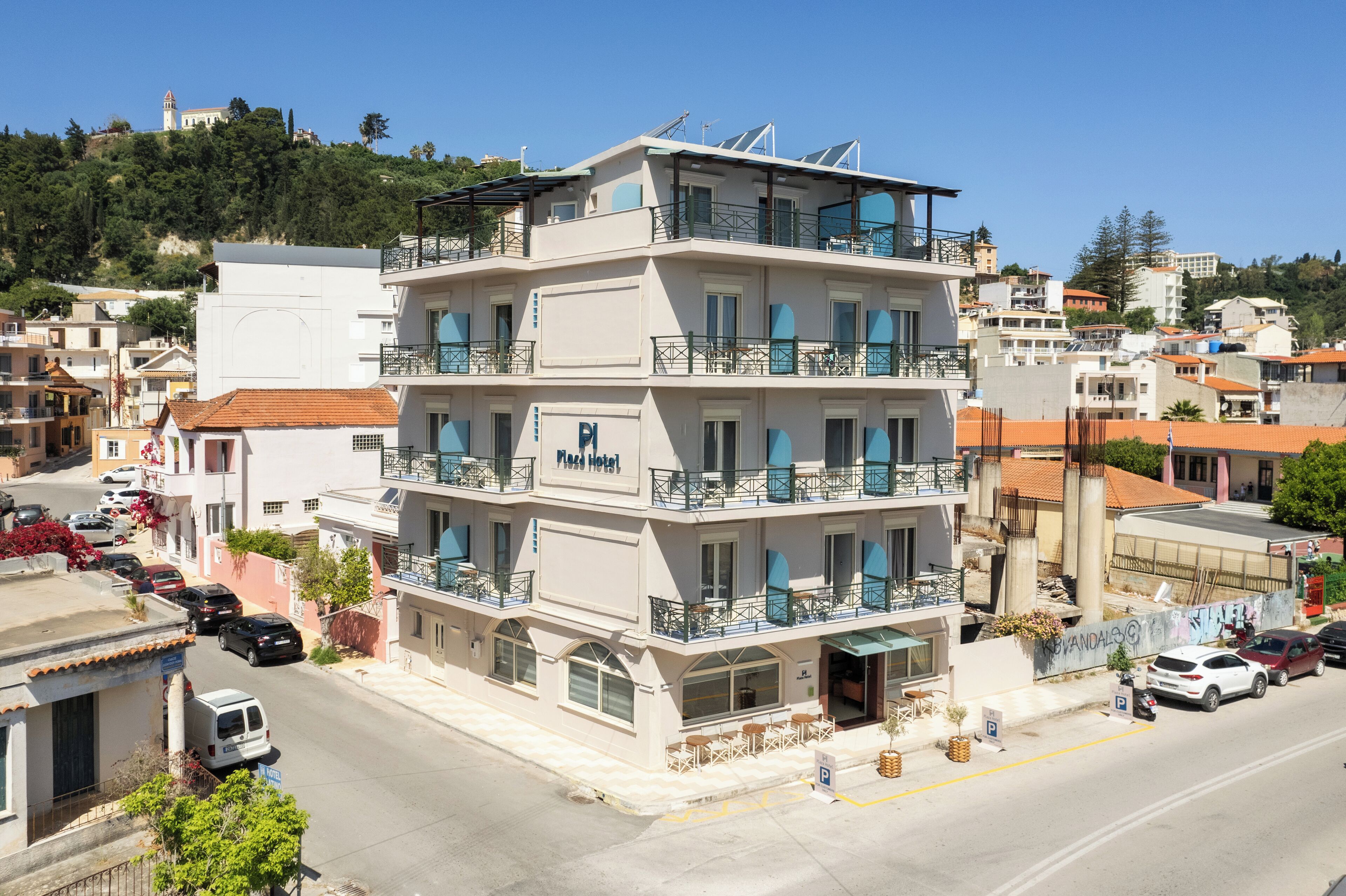 A multi-story hotel with balconies, a parking area, and a view of the surrounding neighborhood.