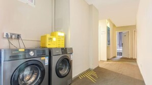 A laundry area with two front-loading washing machines and a yellow box on top. - 100 Inn Shanghai Jiuting Subway Station (Shanghai)