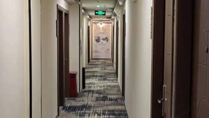 A hotel hallway with patterned carpet, doors on both sides, and a central wall with a decorative mural. - 100 Inn Shanghai Jiuting Subway Station (Shanghai)