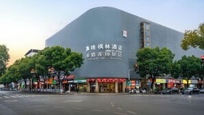 A modern building with a unique curved roof and signage in a foreign language. - 100 Inn Shanghai Jiuting Subway Station (Shanghai)