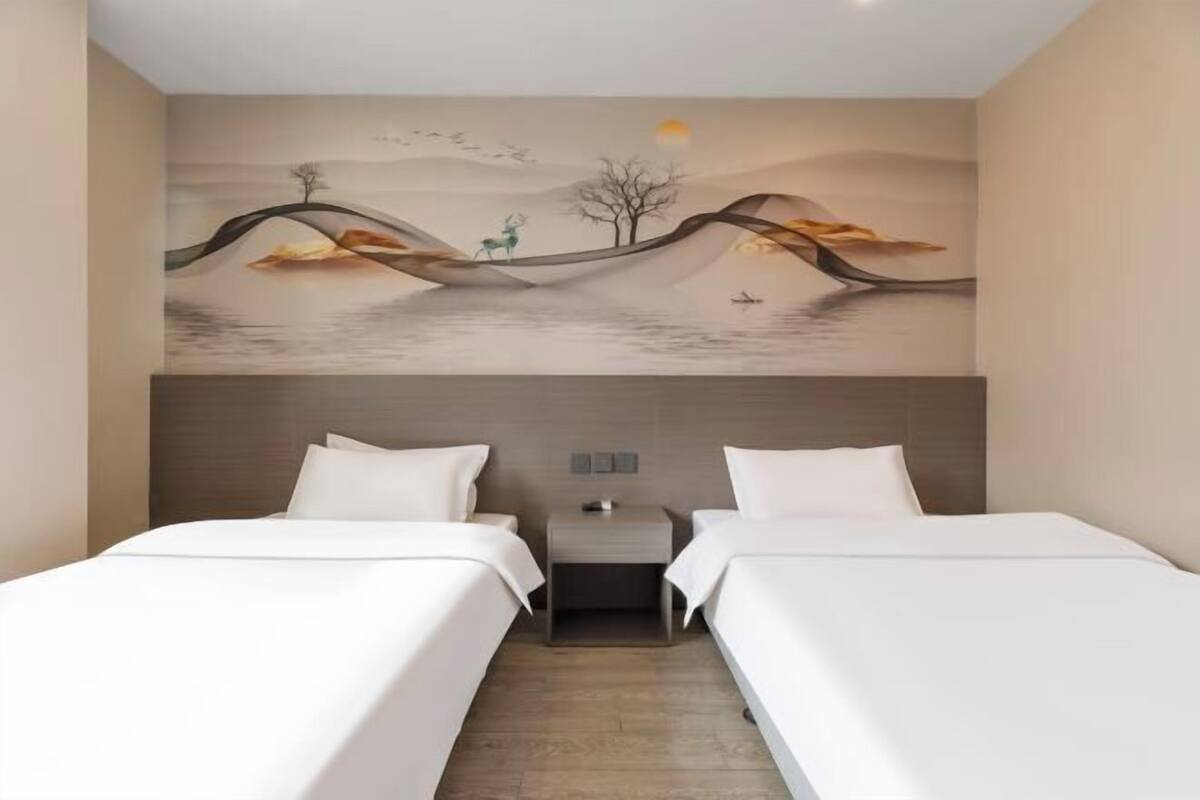 A hotel room with two beds, a nightstand, and a mural on the wall.
