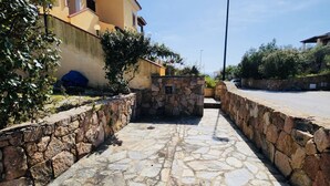 Un camino de piedra que conduce a un edificio, con un muro de piedra a un lado y una calle al otro.