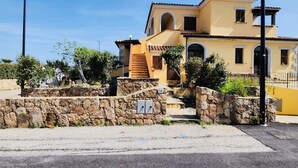 Un edificio amarillo de dos pisos con una escalera de piedra que lleva a la entrada.