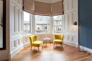 A corner room with two yellow chairs, a small round table, and a floor lamp. - Haymarket - Deluxe Double room (Edinburgh)