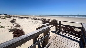 A wooden boardwalk leading to a sandy beach with sparse vegetation and a clear blue sky. - Seabreeze Oasis - Beachy Days, Starry Nights! (Surfside Beach)