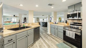 A modern kitchen with grey cabinets, stainless steel appliances, and a wooden floor. - Seabreeze Oasis - Beachy Days, Starry Nights! (Surfside Beach)
