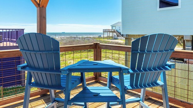A deck with two Adirondack chairs and a small table, overlooking a beach and ocean. - Seabreeze Oasis - Beachy Days, Starry Nights! (Surfside Beach)