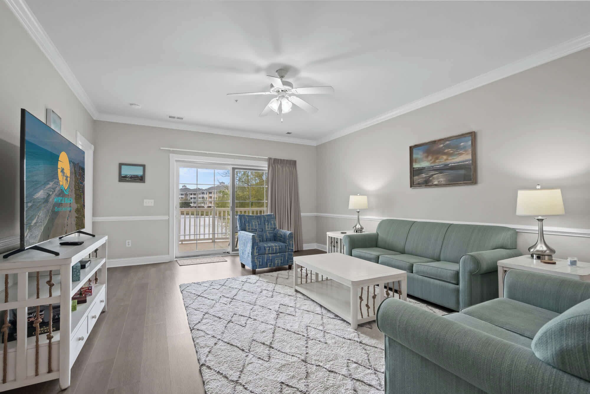 A living room with a sofa, coffee table, TV, and a ceiling fan.