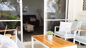 A modern living room with a wooden coffee table, white sofas, and a view through a glass door.
