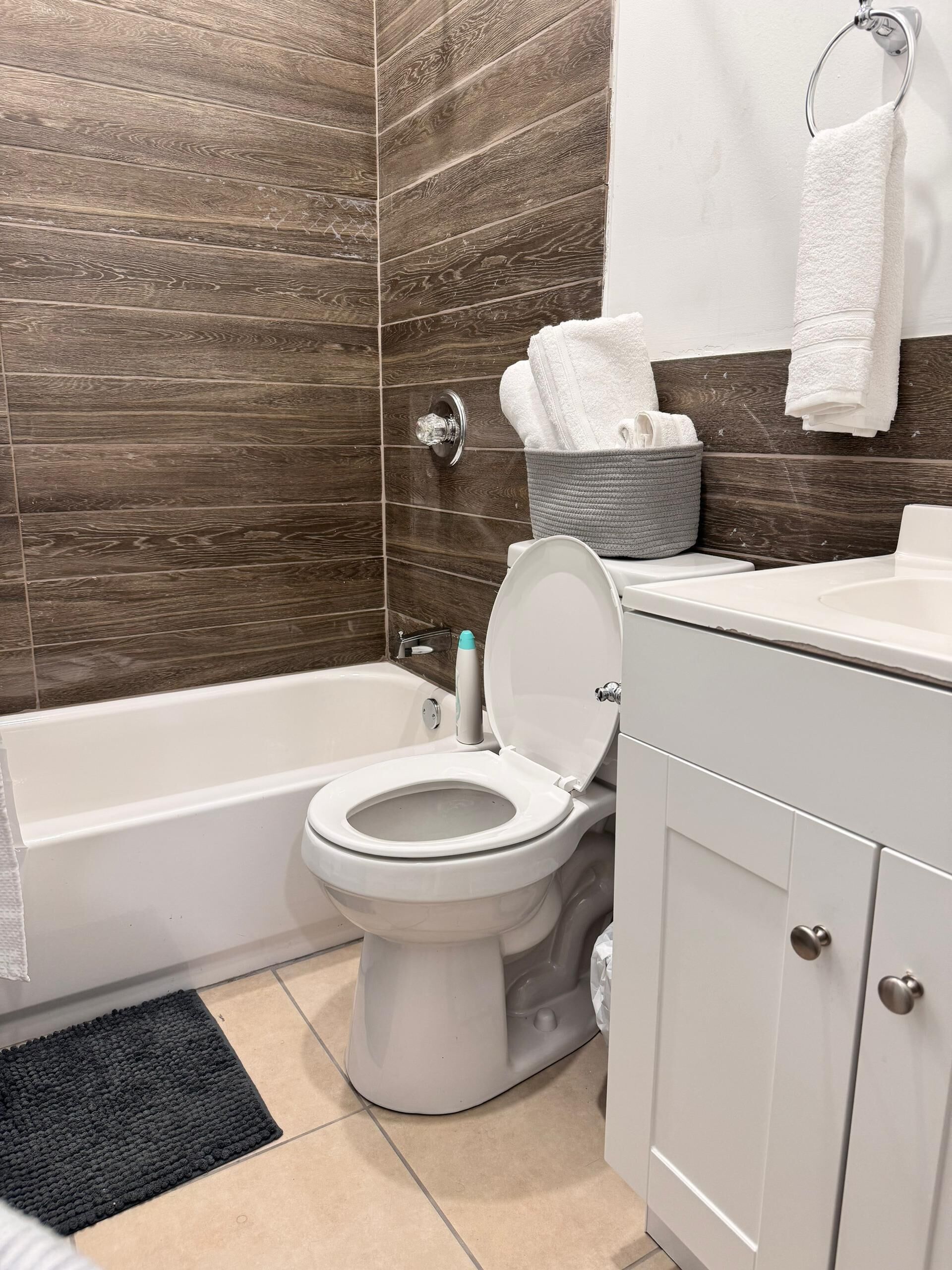 Une salle de bain avec des toilettes blanches, une baignoire, un lavabo et un porte-serviettes.