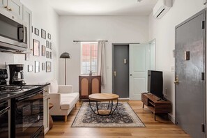 A compact living space with a kitchenette, a sofa, a round coffee table, and a television.