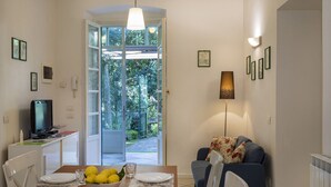 A dining area with a table set for two, a television, and a sofa.