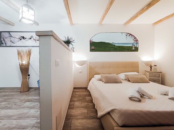 Un dormitorio con cama, mesitas de noche, una lámpara, un cuadro y una lámpara de pared.