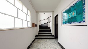 A hallway with a tiled floor, a staircase, and a wall with a decorative tile design.