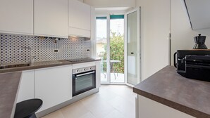 A modern kitchen with white cabinets, a built-in oven, and a large window.
