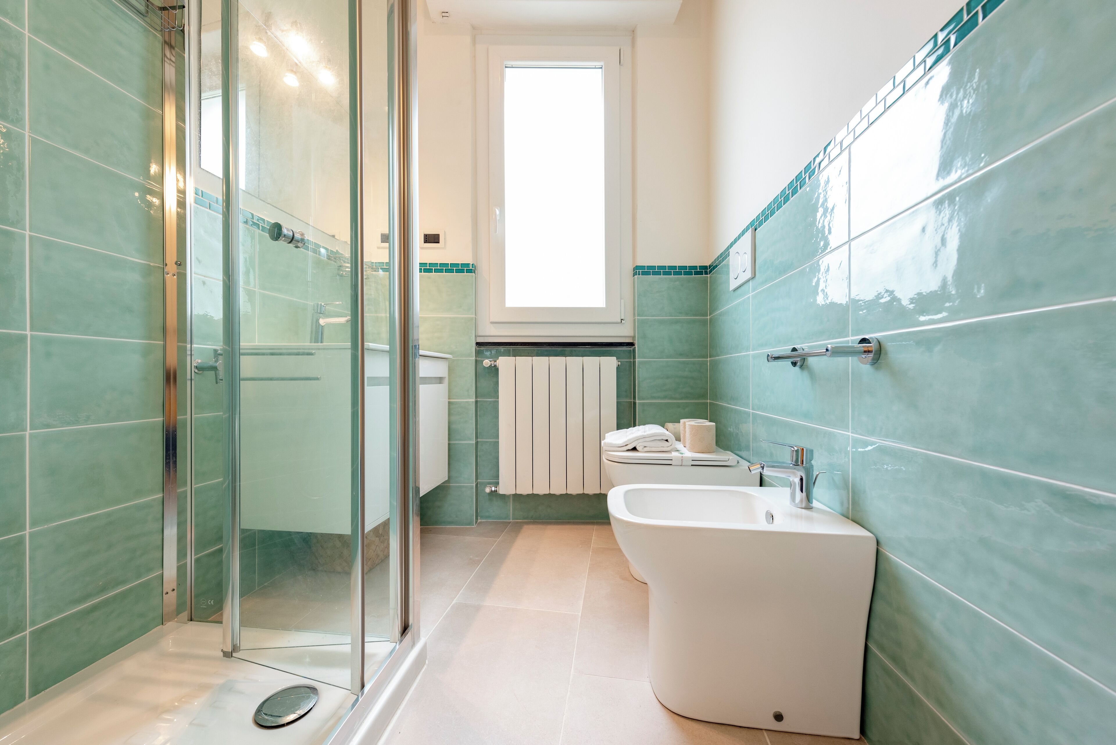 A modern bathroom with a glass shower enclosure, a freestanding bathtub, and a toilet.