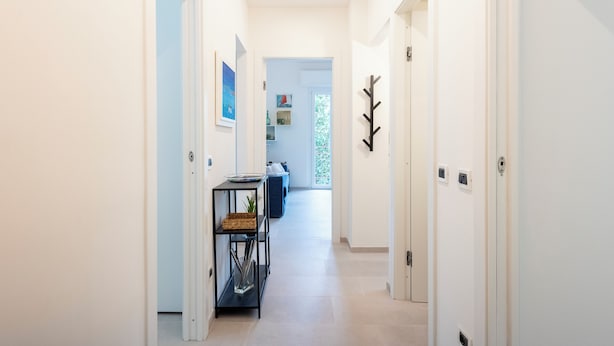 A hallway with white walls, a black console table, and a door with a coat rack.