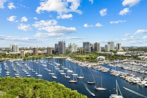 A marina with numerous boats docked, surrounded by a city skyline with high-rise buildings.