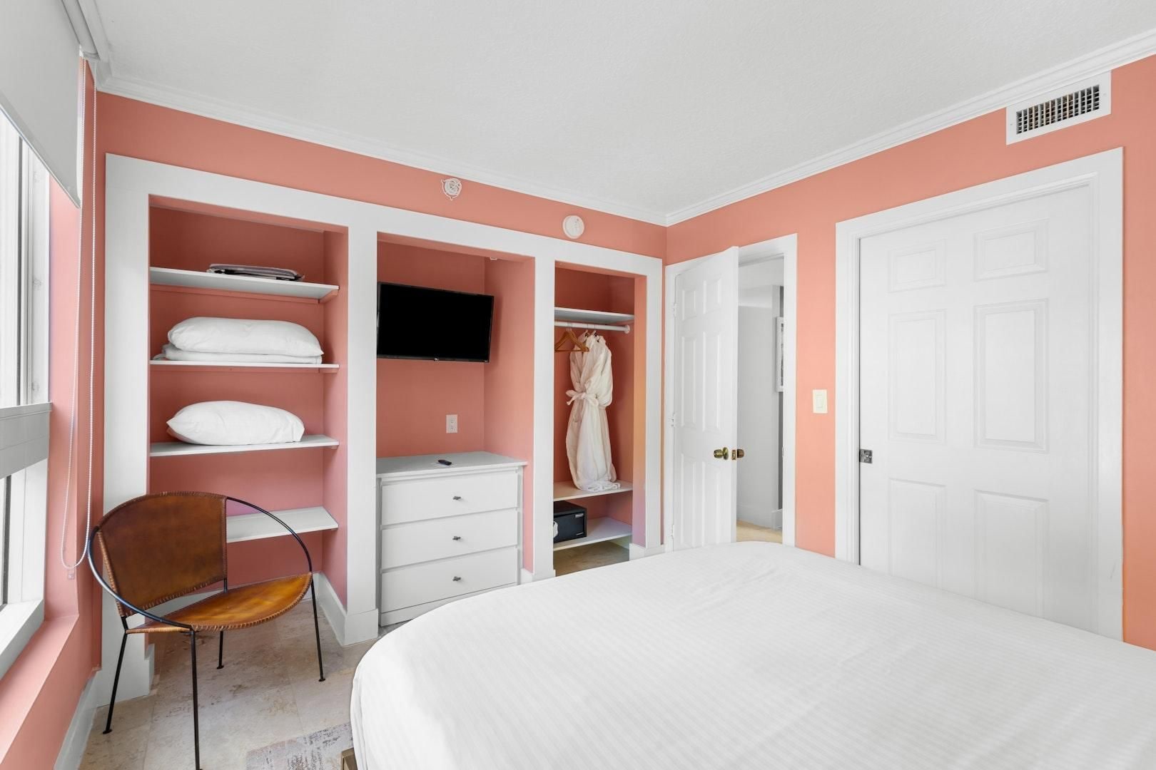 Een slaapkamer met een bed, een stoel, een kledingkast en een televisietoestel.
