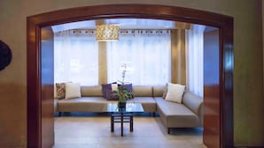 A living room with a sofa, a glass coffee table, and a potted plant.