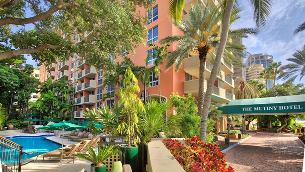 Un hotel con piscina, sedie a sdraio e palme.