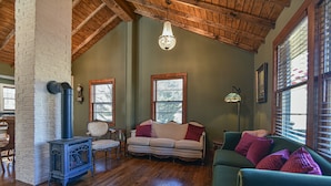 Una sala de estar acogedora con techo de madera, chimenea, sofá y un sillón verde.