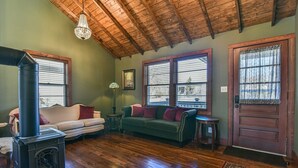Una sala de estar acogedora con techo de madera, chimenea, sofá y puerta con ventanal.
