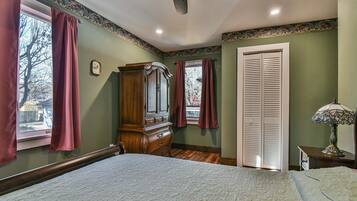 A bedroom with a bed, a dresser, a wardrobe, and a window with curtains.