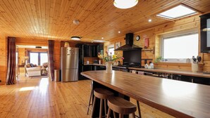 A spacious kitchen with wooden floors and a central island with stools.