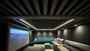 Un cine en casa moderno con una pantalla grande, un sofá y un techo con diseño de estrellas.