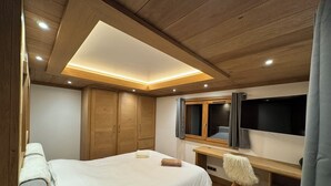 Un dormitorio con cama, armario de madera, escritorio y televisor.