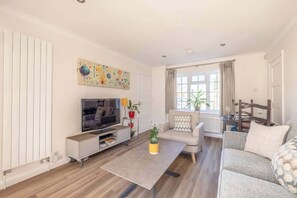 A modern living room with a sofa, coffee table, TV, and artwork on the wall.