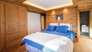 Un dormitorio con una cama grande, un armario de madera y una ventana pequeña decorada con un adorno de árbol.
