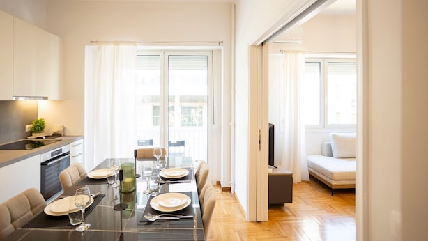 A modern kitchen with a dining area, a sofa, and a TV in a living space. - Elegant 3-bedroom Retreat in the Heart of Kolonaki (Athens)