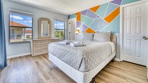 Une chambre à coucher comprenant un lit, une commode et une décoration murale géométrique.