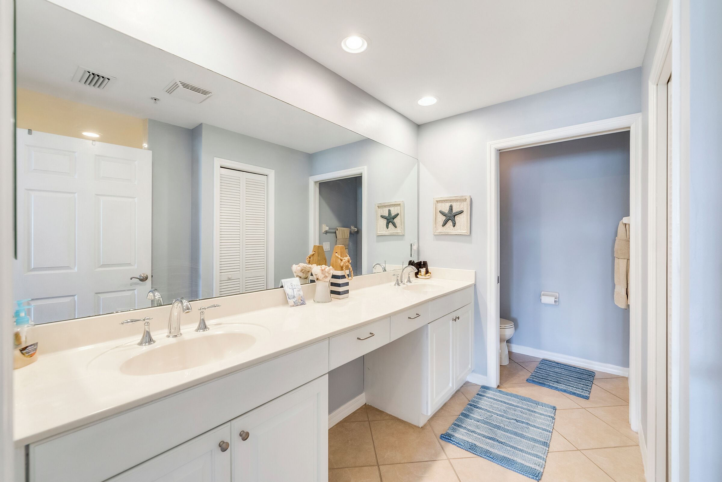 A bathroom with a double sink, a large mirror, and a toilet.