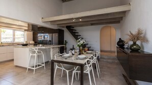 A modern kitchen with a central island, bar stools, and a dining table set for six.