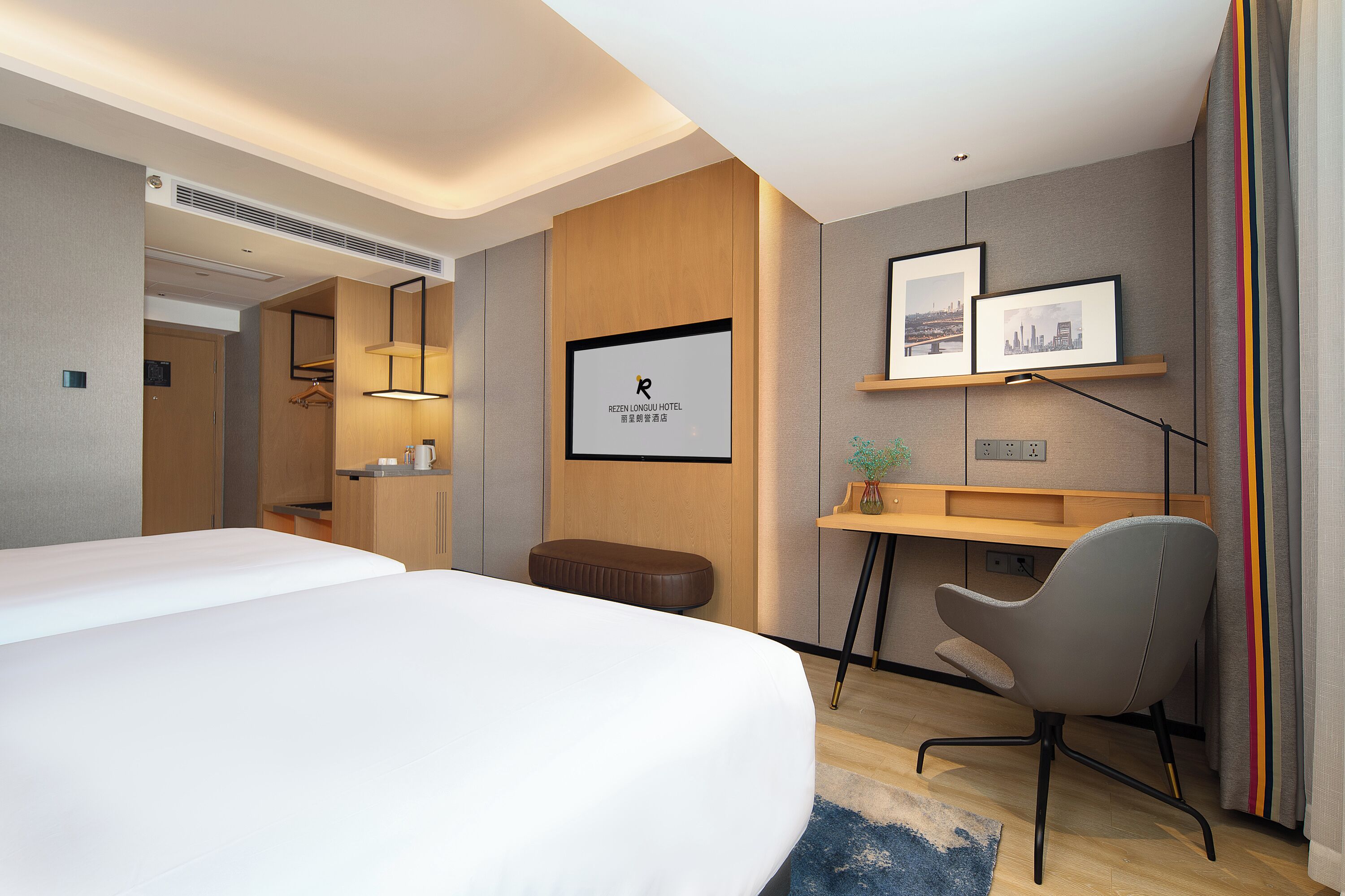 A modern hotel room with a large bed, a desk, a chair, and a small table with a plant.