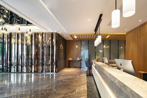 Una moderna zona de recepción con suelo de mármol, paneles de madera y varios Apple iMacs sobre el mostrador.