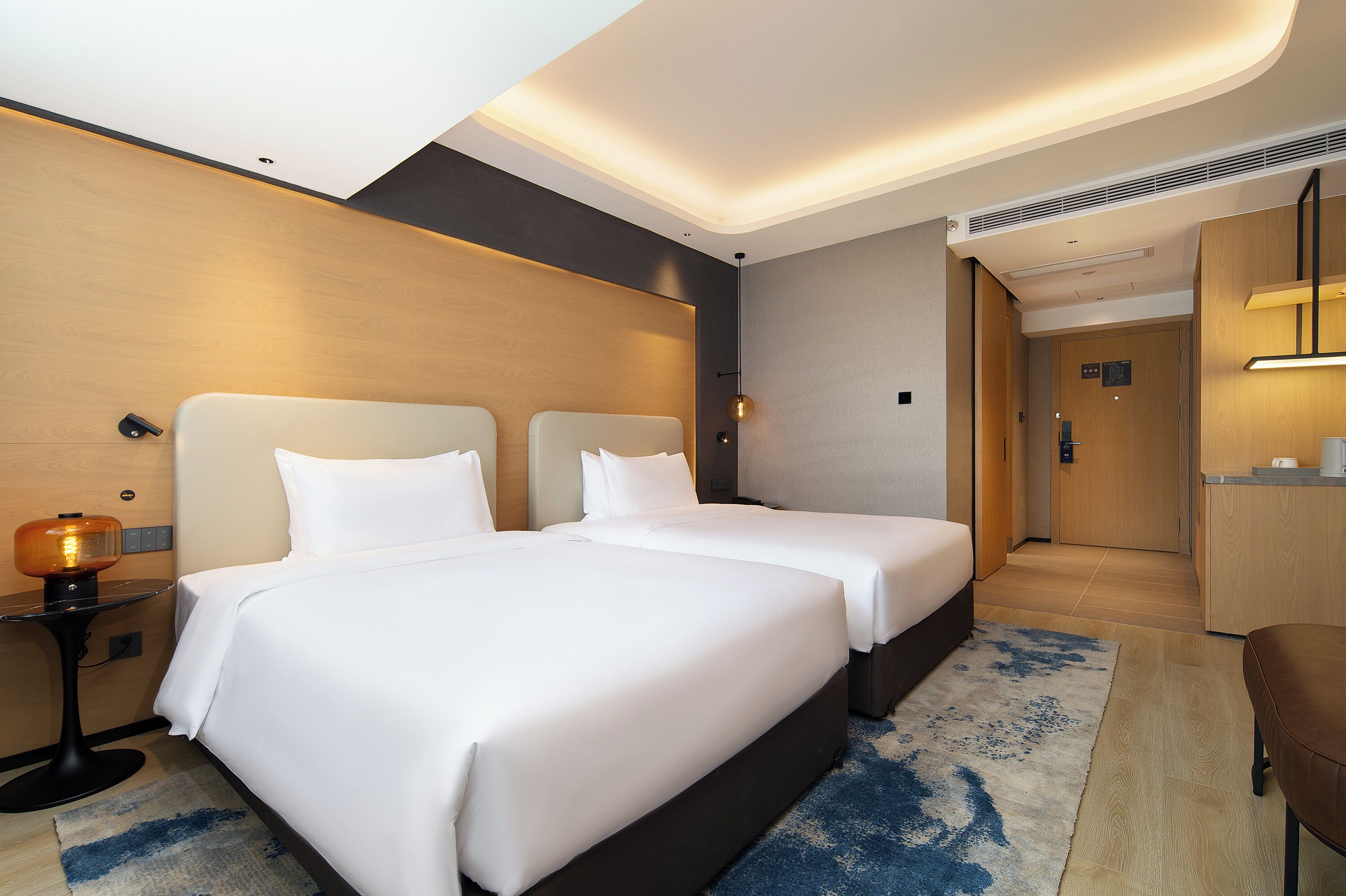A hotel room with two beds, a desk, and a small seating area.