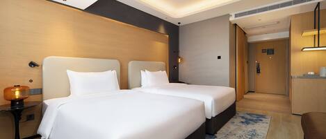 A hotel room with two beds, a desk, and a small seating area.