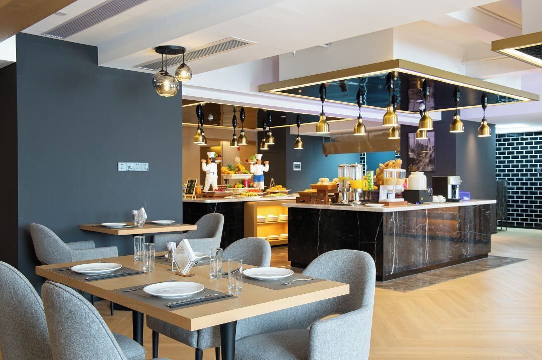 A modern dining area with a central island, grey upholstered chairs, and pendant lighting.