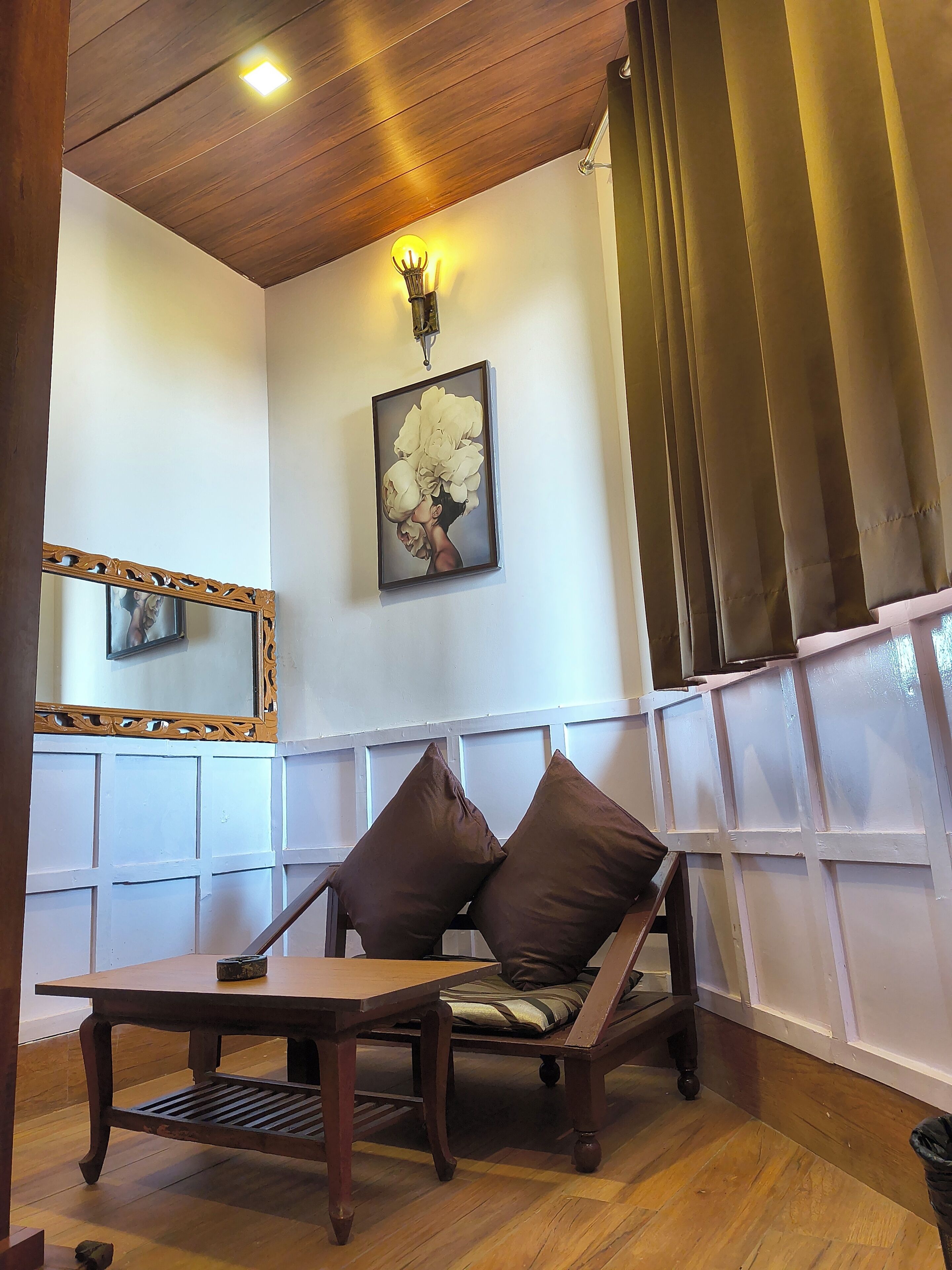 Una stanza con soffitto in legno, un quadro incorniciato, una panca imbottita e un tavolo.
