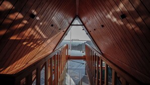 A wooden interior with a glass ceiling and a view of the outside. - The Offroad Homestay (Dehradun)