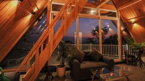 A cozy interior with a wooden staircase, a sofa, and a glass table. - The Offroad Homestay (Dehradun)
