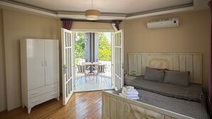 A bedroom with a bed, a wardrobe, and an open door leading to a balcony. - Kekik Alaçatı Otel (Cesme)