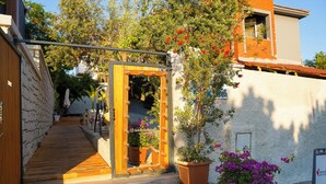 A wooden staircase leading to a doorway with a mirror, potted plants, and a signboard. - Kekik Alaçatı Otel (Cesme)