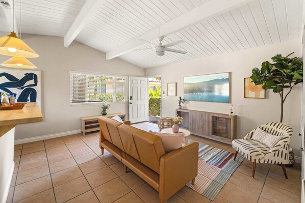 A living room with a sofa, a chair, a fireplace, and a ceiling fan.