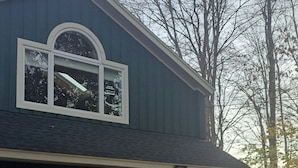 A two-story house with a dark blue exterior, a large arched window, and two garage doors. - Mid Century Modern Studio w/ Full Kitchen - Newly Built (Kent)