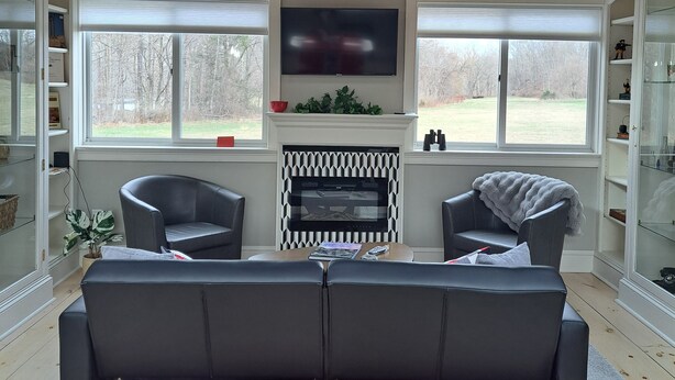 A living room with a fireplace, two armchairs, a sofa, and a TV. - Mid Century Modern Studio w/ Full Kitchen - Newly Built (Kent)